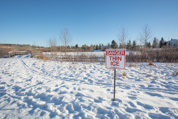 thin ice sign with footprints in the snow