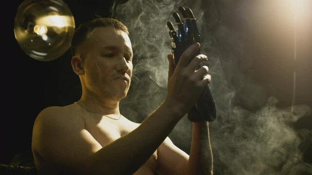 A disabled man without an arm puts on a bionic prosthesis on a stump. A full-fledged life of a guy with an artificial hand, controlled by the intellect. New technologies in robotics. Cinematic shot.