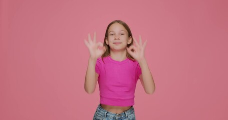 Funny child girl showing ok gesture, make glasses by fingers, having fun, fooling on pink background. Positive feedback