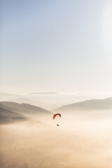 Red parachute in the sky above the mountains during sunset