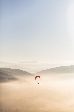 Red parachute in the sky above the mountains during sunset