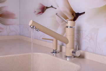 Sand-colored kitchen faucet from which cold water flows