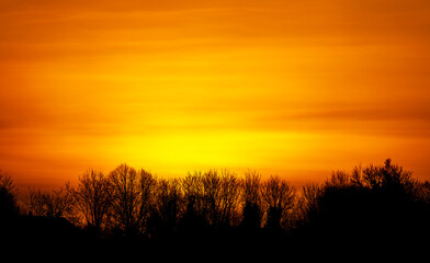 Obraz na płótnie Canvas a powerful intense sunrise fills the horizon with a fiery blanket of red, orange and yellow, Wiltshire UK