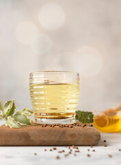 Cup with buckwheat tea, granules and honey, light grey background. Superfood Taiwan Ku Qiao buckwheat tea and grits of tartary buckwheat. Detox and healthy food.