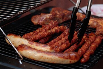Grilled meat on a gas grill with grill tongs