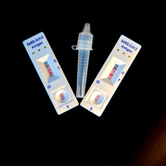 2 covid-19 antigen self-tests positive and buffer bottle on black background. Self test. test at...
