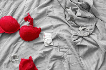 Female lingerie with condoms and handcuffs on bed after romantic date