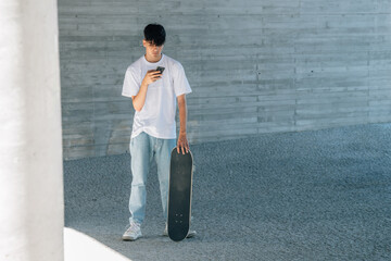 young man with mobile phone and skateboard in the city