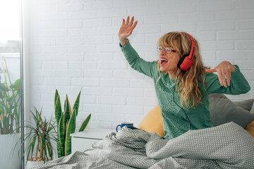woman with headphones in bedroom happy