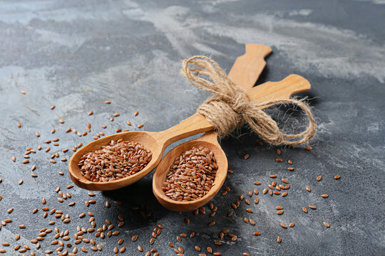 Spoons with flax seeds on color background