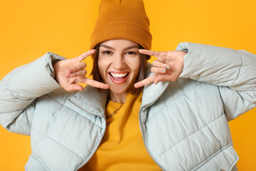 Cool young woman in stylish warm clothes on color background