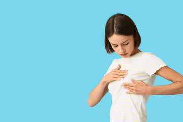 Young woman feeling discomfort in her breast on color background. Cancer awareness concept