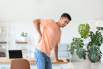 Young man feeling back pain at home