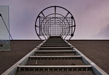 Drabina do nieba. Wyjście na dach , drabinka ( schodki) metalowa  na tle ściany . Ladder to heaven. Access to the roof, metal steps against the wall background.  © Grzegorz