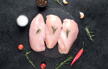 Three raw chicken breasts on stone background