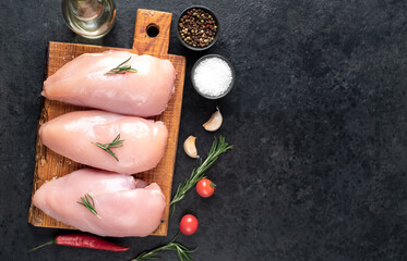 Fototapeta na wymiar Three raw chicken breasts on stone background with copy space for your text