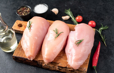 Three raw chicken breasts on stone background