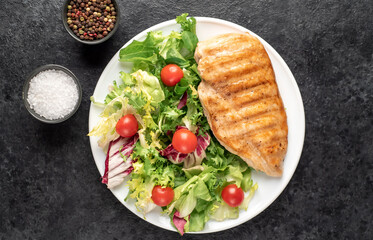 grilled chicken breast and cherry tomato salad on stone background
