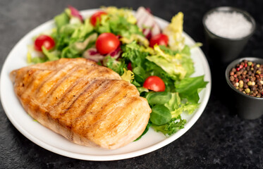 grilled chicken breast and cherry tomato salad on stone background