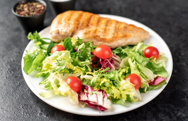 grilled chicken breast and cherry tomato salad on stone background
