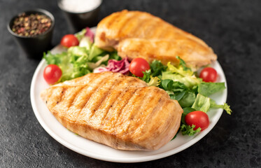 grilled chicken breast and cherry tomato salad on stone background