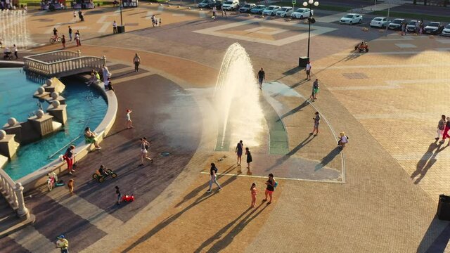 happy children joyfully run through the jets of fountains in the city square. Symbol of kindness, family, prosperity and happiness
