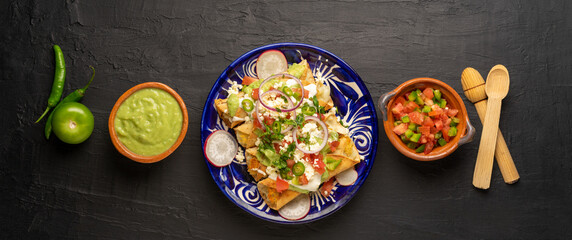 Mexican fried potato tacos called flautas with guacamole and cheese