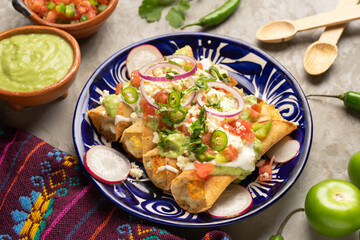 Mexican fried potato tacos called flautas with guacamole and cheese