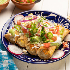 Mexican fried potato tacos called flautas with guacamole and cheese