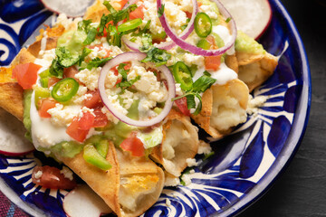 Mexican fried potato tacos called flautas with guacamole and cheese