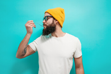 Portrait of handsome man with beard wearing glasses enjoying delicious meal with fork in studio...