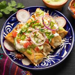 Mexican fried potato tacos called flautas with guacamole and cheese