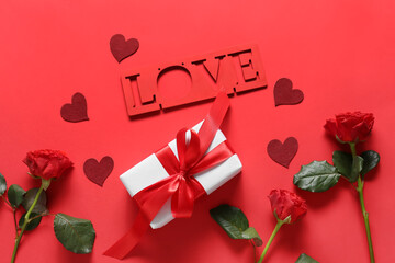 Composition with gift box, rose flowers and word LOVE on red background. Valentine's Day celebration