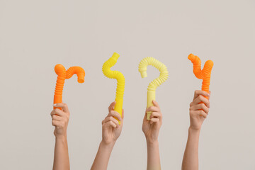 Hands with popular pop tubes on light background