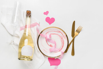 Stylish table setting for Valentine's Day and bottle of champagne on light background
