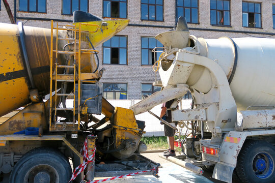 Concrete Truck Loads Concrete Pump Truck at Construction Site. Selective focus.