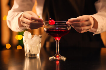 Bartender preparing tasty Manhattan cocktail at table in bar