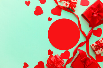 Composition with blank card, paper hearts and gift boxes on color background. Valentine's Day celebration