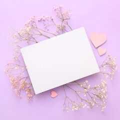 Composition with blank card, gypsophila flowers and paper hearts on lilac background. Valentine's Day celebration