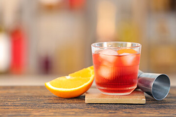 Glass of tasty Negroni cocktail on table against blurred background