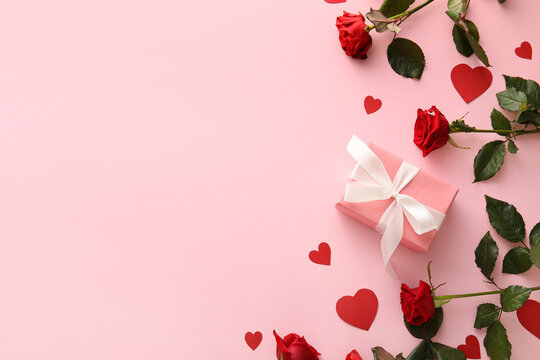 Composition with gift for Valentine's Day, paper hearts and rose flowers on pink background