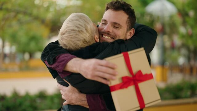 Mother and son smiling confident surprise with birthday gift at park
