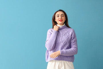 Pretty young woman in warm sweater on color background