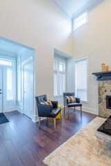 Beautiful and large living room interior with hardwood floors and vaulted ceiling in new luxury home. View of entryway, and second story loft style area
