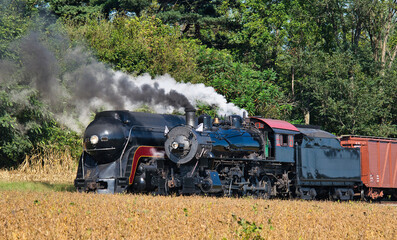 Two Antique Steam Locomotives That Were Built Almost Fifty Years Apart All Blowing Smoke and Steam Waiting to Go.