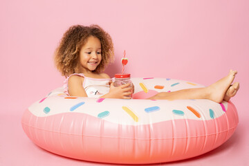 Obraz na płótnie Canvas Portrait of happy little girl with inflatable rubber circle having fun isolated on pink background