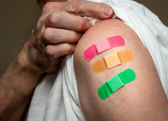 Senior caucasian man sleeve to show the third booster coronavirus vaccine shot in the shoulder. Concept with three separate bandages for the shots - obrazy, fototapety, plakaty