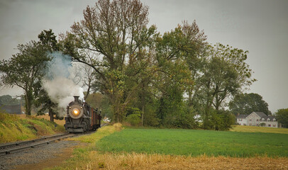 Obraz premium An Antique Restored Steam Freight Train Approaching Head on Blowing Smoke and Steam