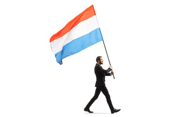 Full length profile shot of an elegant man in a suit walking and carrying a dutch flag