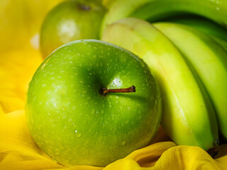 Green apple and green bananas on the yellow cloth 